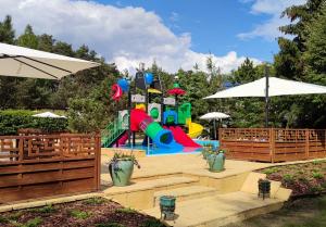 a playground with a slide in a park with umbrellas at Farma Jantar in Jantar