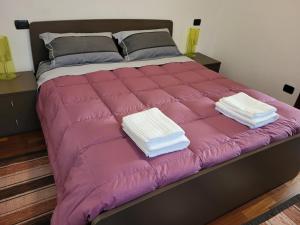 - un grand lit rose avec 2 serviettes pliées dans l'établissement Residence Belvedere Apartment Bolvedro, à Tremezzo