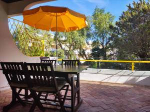 een tafel en 2 stoelen met een parasol op een patio bij Golden Beach Vilamoura in Quarteira