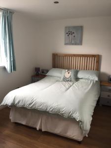 a bedroom with a white bed with a stuffed animal on it at The Grooms Quarters in Loughor