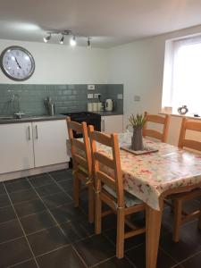 a kitchen with a table and chairs and a clock on the wall at The Grooms Quarters in Loughor