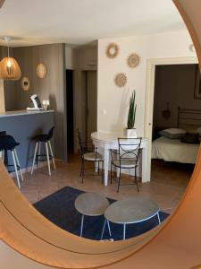 a living room with a table and chairs and a mirror at appartement cosy avec climatisation réversible GOLF DE SAUMANE in Saumane-de-Vaucluse