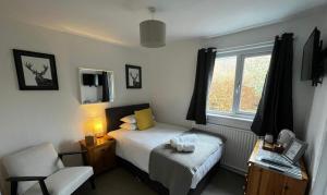 a bedroom with a bed and a chair and a window at Loch Eyre House in Portree