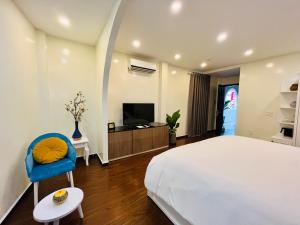 ein Schlafzimmer mit einem Bett, einem TV und einem blauen Stuhl in der Unterkunft Chez Mimosa Corner - New address 90 Đề Thám in Ho-Chi-Minh-Stadt