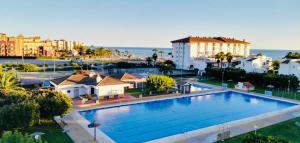 a large swimming pool in a city with buildings and the ocean at Casa Pandora Apartamento Duplex Atico, primera línea de playa Torrox in Torrox Costa