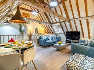 sala de estar con mesa, sillas y TV en Haberdashers Loft, en Bungay