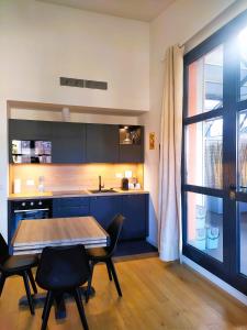 een keuken met blauwe kasten en een tafel en stoelen bij Nuovo Loft con terrazzo M2 IEO Humanitas Bocconi Navigli in Milaan