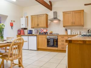 a kitchen with wooden cabinets and a table with a chair at Dragonfly - Uk42521 in Aldwincle Saint Peter
