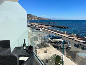 einen Balkon mit Autos, die neben dem Meer geparkt sind in der Unterkunft I Mori dell’Etna in Giardini-Naxos
