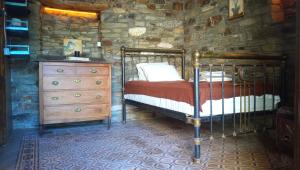 1 dormitorio con 1 cama y vestidor en una pared de piedra en The Aged Olive Tree, en Raches