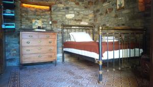 a bedroom with a bed and a dresser in a stone wall at The Aged Olive Tree in Raches