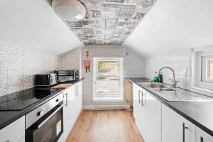 una cucina con armadi bianchi e soffitto di St Augustines 10 Bed Themed House a Kent