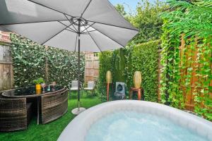 a backyard with a hot tub and an umbrella at St Augustines 10 Bed Themed House in Kent