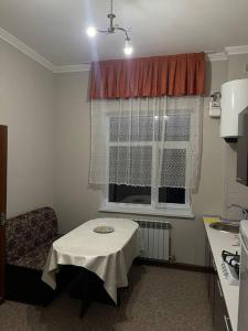 eine kleine Küche mit einem Tisch und einem Fenster in der Unterkunft Mondial apartments in Schymkent