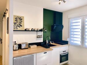 uma cozinha com armários brancos e paredes verdes em L'alcôve - Parking, Calme, Terrasse em Castres
