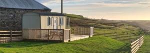 a tiny house on a hill with a wooden deck at North Muasdale Farm - Byre View in Muasdale