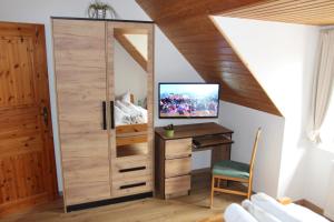 ハイルバート・ハイリゲンシュタットにあるIm Herzen Deutschlands entspannenのデスクとテレビが備わる客室です。