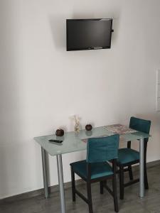 un tavolo con due sedie e una televisione su una parete di Helena's Studio Agia Triada a Agia Triada