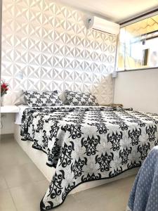 een slaapkamer met een bed met een zwart-wit dekbed bij Flat por temporada in São José da Coroa Grande