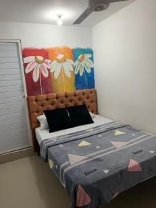 1 dormitorio con 1 cama con una pintura en la pared en Hostal Sabanero en Barranquilla