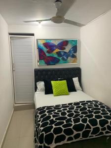 1 dormitorio con 1 cama y una pintura en la pared en Hostal Sabanero en Barranquilla
