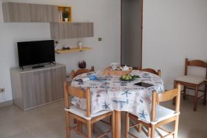 una sala da pranzo con tavolo, sedie e TV di Appartamento Maestrale a Torre Pali