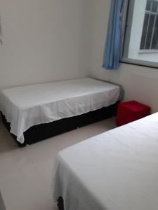 1 dormitorio con 2 camas y un taburete rojo en Apartamento Temporada Dalva Copacabana 2, en Río de Janeiro