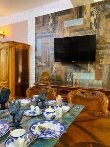 Shirbakyan Boutique Hotel & Apartments في يريفان: غرفة طعام مع طاولة وتلفزيون على الحائط