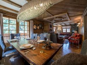 ein Esszimmer mit einem Holztisch und einem Kronleuchter in der Unterkunft Duplex de Charme à Courchevel 1850 - Capacité 10 Personnes, Centre-Ville - FR-1-575-29 in Courchevel