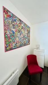 uma cadeira vermelha num quarto com um quadro na parede em Superbe appartement Vue Mer et Piscine em Bandol