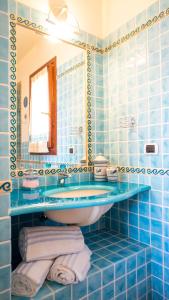Baño de azulejos azules con lavabo y espejo en Villa Patrizia con piscina privata, en Stintino