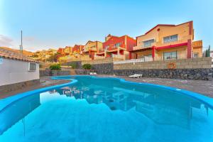 een zwembad met blauw water voor sommige gebouwen bij Calma Paraiso in Playa Paraiso