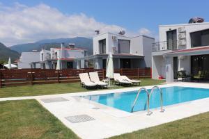 a villa with a swimming pool in front of a house at OLYMPUS Paradise 5 in Skotina