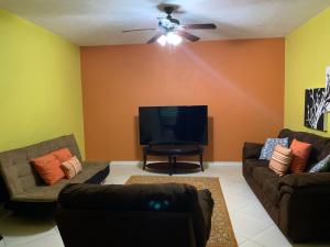 sala de estar con 2 sofás y TV de pantalla plana en CS Domaine Garden Villa - 2 Bedrooms en Port Antonio