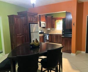 una cocina con mesa y sillas y una cocina con armarios de madera. en CS Domaine Garden Villa - 2 Bedrooms en Port Antonio