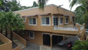 Casa amarilla con balcón y palmeras en CS Domaine Garden Villa - 2 Bedrooms en Port Antonio