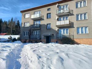 un edificio con un montón de nieve delante de él en Zlatá Olešnice, pomezí Jizerek a Krkonoš, en Zlatá Olešnice