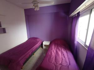two beds in a room with purple walls and a window at Depto Caba Floresta in Buenos Aires