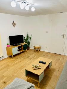 ein Wohnzimmer mit einem Couchtisch und einem Flachbild-TV in der Unterkunft LA RUELLE ALSACIENNE, Charme Alsacien et Confort Moderne in Riquewihr