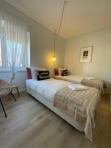 a bedroom with two beds and a chair at The Swallows Nest in Lisbon