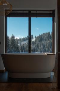 a bath tub in a room with a large window at Chillax Chalet in Yablunytsya