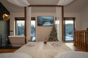 a bedroom with two beds and a tub and a christmas tree at Chillax Chalet in Yablunytsya