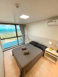 ein Schlafzimmer mit einem großen Bett und einem großen Fenster in der Unterkunft Paiva (Barra Home Stay) Luxuoso - vista incrível 26 andar in Recife