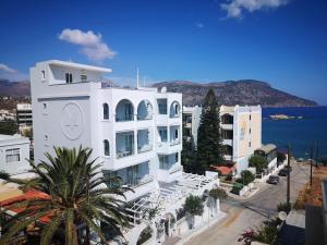 a white building with a clock on the side of it at ALOS SUITES ex-Possirama Bay aparts in Karpathos