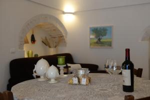 a table with a bottle of wine and glasses on it at BORGANTHIA in Alberobello