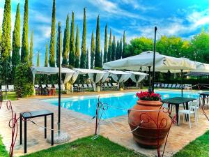 a pool with tables and umbrellas and a vase with flowers at Mapepa Village apartments in Spello