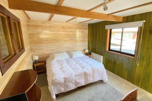 1 dormitorio con 1 cama y pared de madera en MI Lodge Las Trancas Hotel & Spa en Las Trancas
