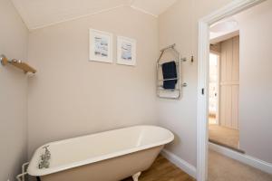 a white bathroom with a bath tub in it at Rose Cottage, Snettisham, Norfolk in Snettisham