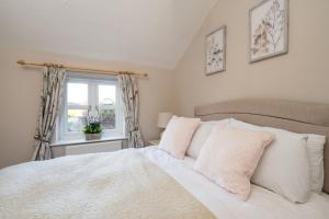 a bedroom with a white bed and a window at Rose Cottage, Snettisham, Norfolk in Snettisham