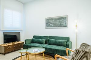 ein Wohnzimmer mit einem grünen Sofa und einem Tisch in der Unterkunft Apartmentos Marqués de Nervion in Sevilla